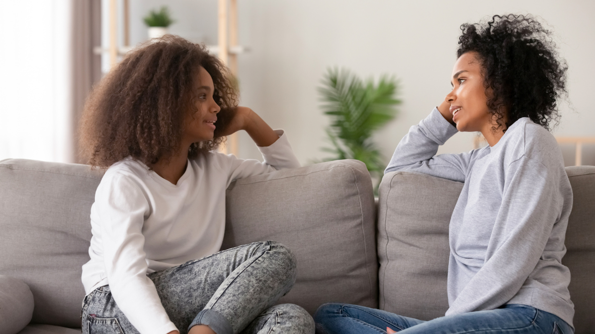 A mother and daughter chatting on a sofa.