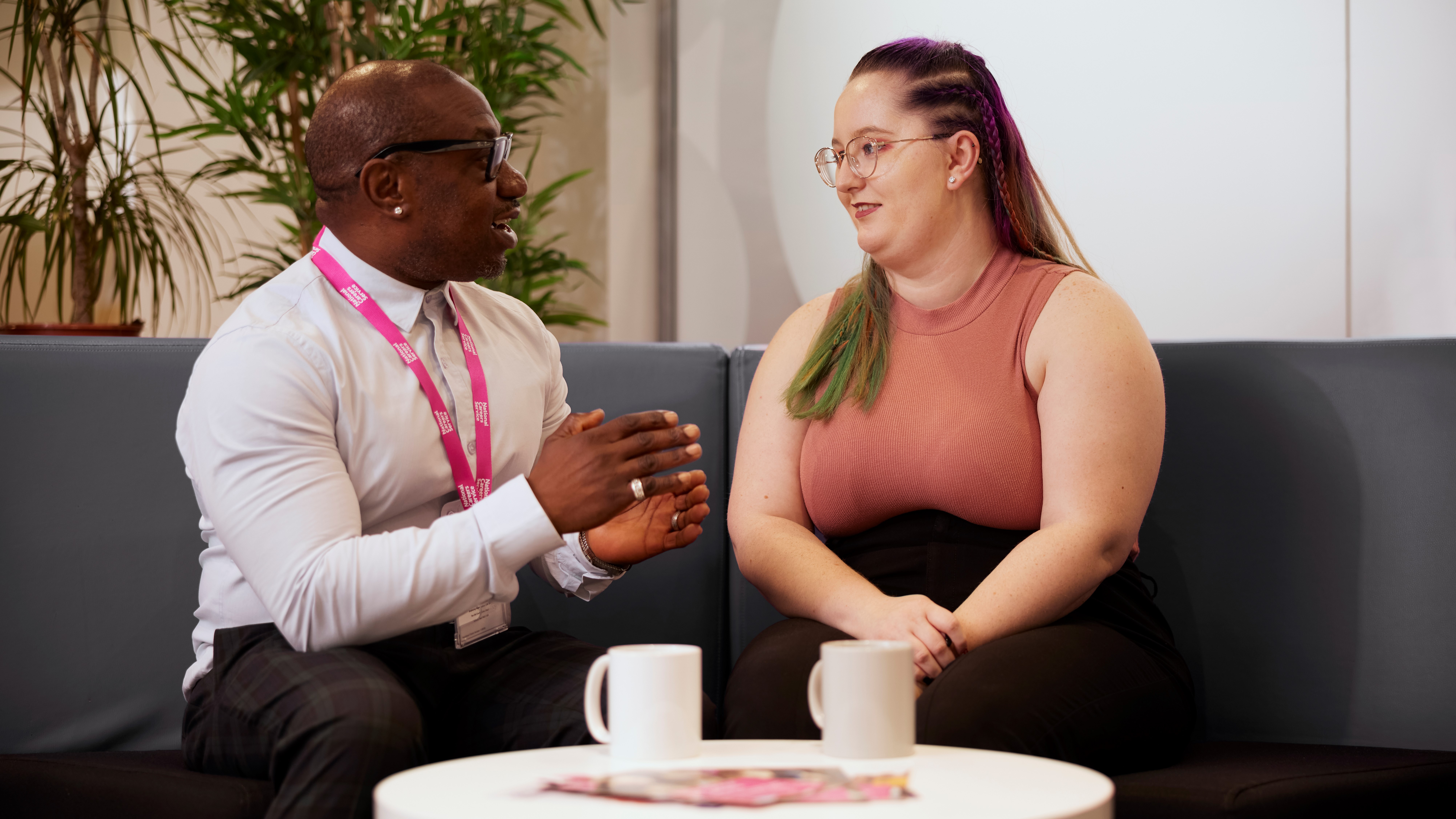 A white woman and Black careers adviser are sitting and talking on a sofa.