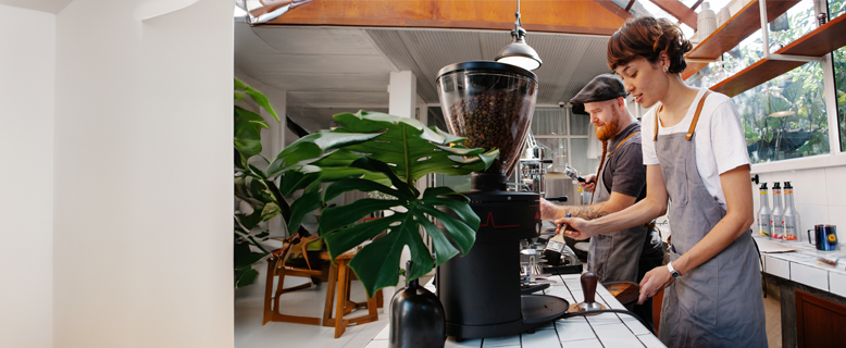 Hospitality staff working at a coffee machine.