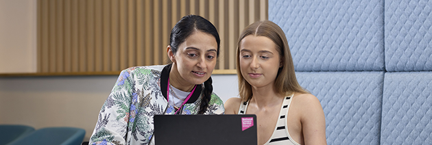 Two people looking at a single laptop together with interest.