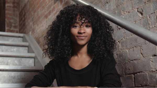 A woman sitting on a metal staircase next to a brick wall.