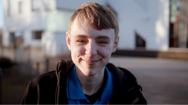 A man stood outside a building and smiling.