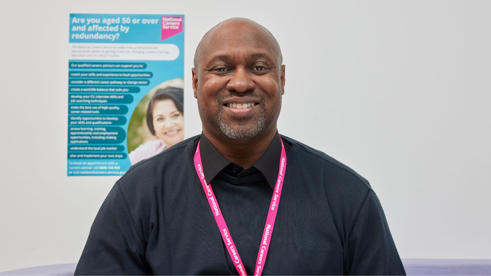 Man with a pink lanyard on, smiling straight at the camera