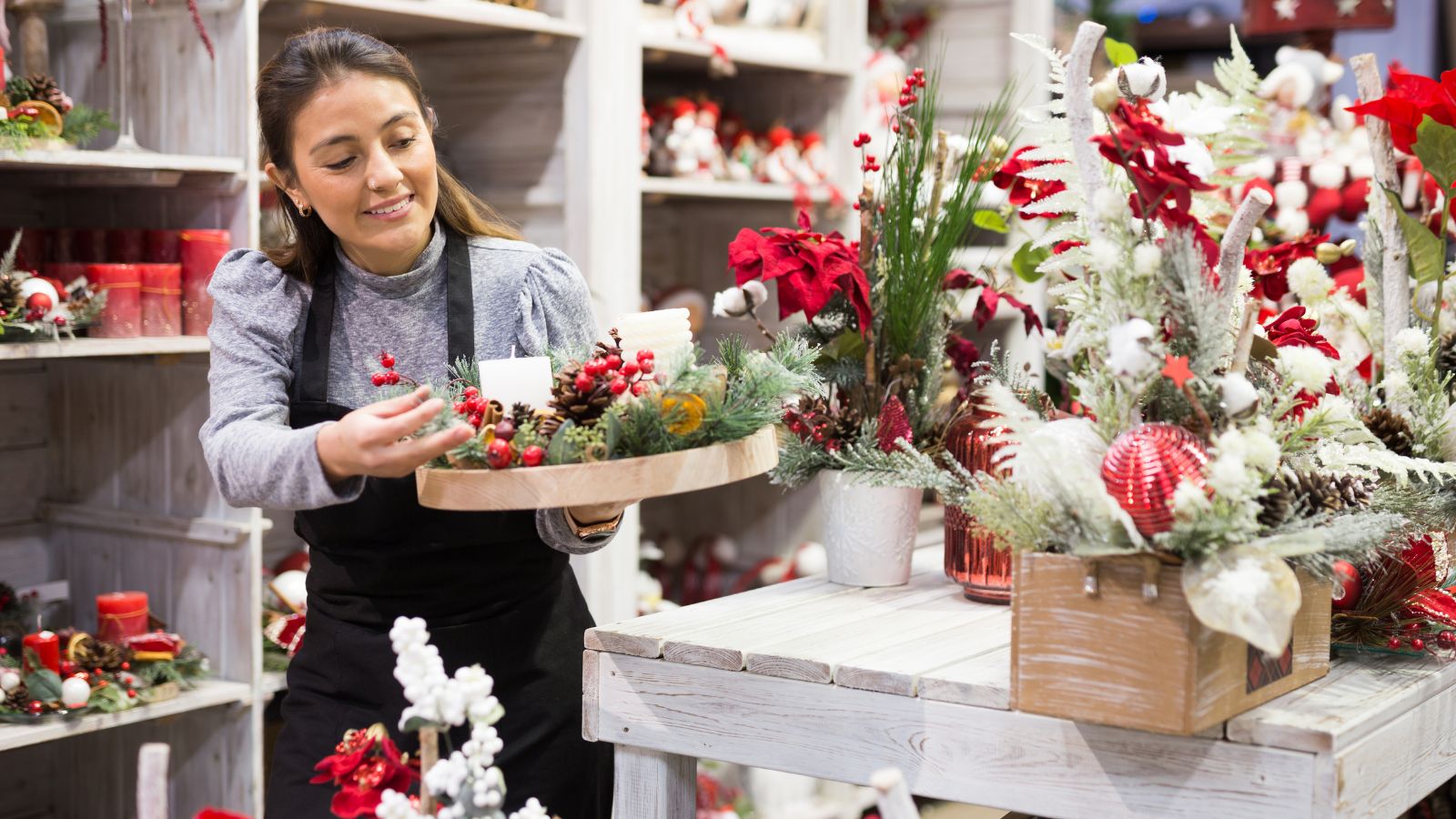 A retail assistant carrying a holly wreath