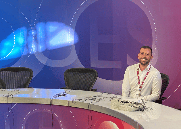 Man sitting at a desk in a TV studio.